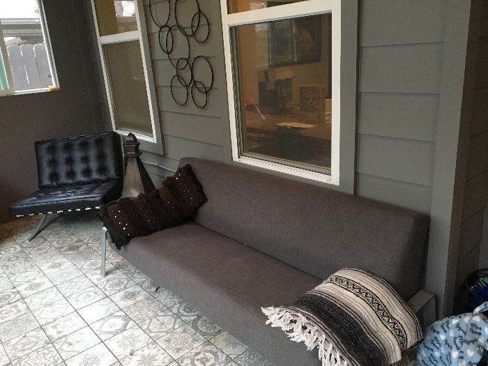 Grey couch (there are 2). Mexican blankets, Pillows. Large metal home pillars. Black lounge chair.