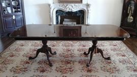 Custom made banquet size double pedestal table with two leaves and pads. Handwoven needlepoint rug.