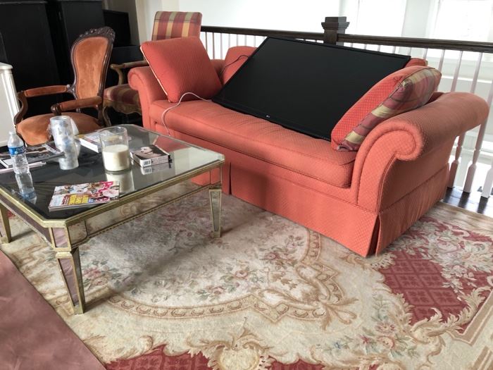 Salmon colored sofa, mirror coffee table & area rug 
