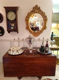 Wonderful drop-leaf American Empire mahogany dining table, with two very large silverplated serving trays, set/12 Towle silverplated mint julep cups, pair of 3-light sterling silver candelabra, silverplated samovar, with nicely detailed gold wood/beveled glass wall mirror and vintage "Regulator" wall clock. The clock works very well and has very pleasant chimes at the quarter hour.