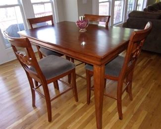 Bar height table with center pull-out leaf and 6 chairs with light gray padded seats, in excellent condition.