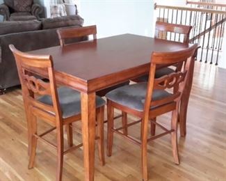 Bar height table with center pull-out leaf and 6 chairs with light gray padded seats, in excellent condition.