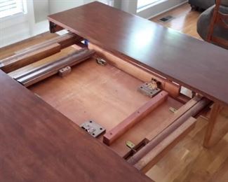 Bar height table with center pull-out leaf and 6 chairs with light gray padded seats, in excellent condition.