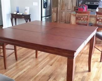 Bar height table with center pull-out leaf and 6 chairs with light gray padded seats, in excellent condition.