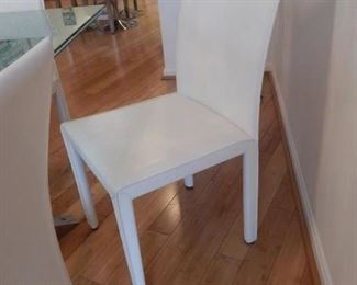 Set of six white leather dining room chairs.