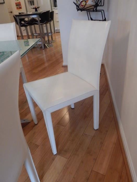 Set of six white leather dining room chairs.