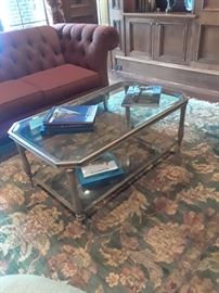 Glass and brushed metal coffee table atop floral rug