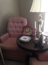 One of two pink bedroom chairs; round side table, lamp, and brass candlesticks