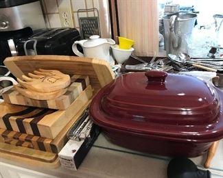 Tables and counters full of kitchen ware, cutting boards, baking dishes, pots and pans, small appliances and more.