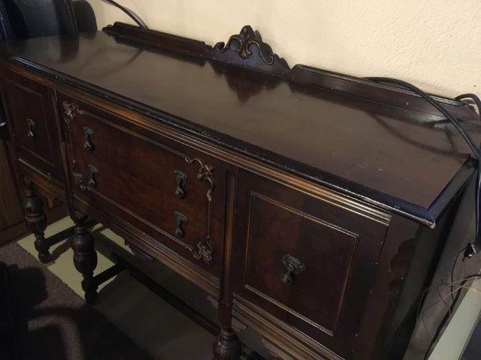 Walnut sideboard is from the 1940's era with a lot of character features of metal cabinet knobs, and scroll moldings on door fronts and back board, that accentuates it's uniqueness.