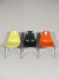 Eames design molded plastic chairs in yellow, black and orange, mid-century, with metal legs. Unmarked, but produced by Herman Miller.