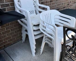 Four larger plastic white chairs against the brick have sold