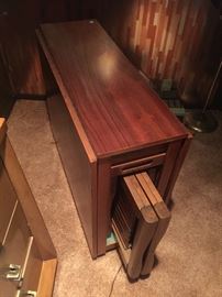 Mid Century table with hidden compartment for folding chairs. 