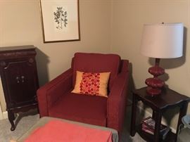 Upholstered arm chair, side table, table lamp, foot rest, botanical print, jewelry armoire.