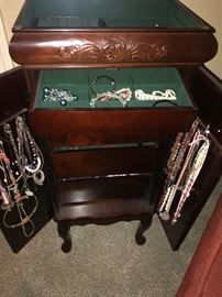 Wooden jewelry armoire and costume jewelry.