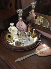 A selection of perfume bottles, hand mirror and mirror tray