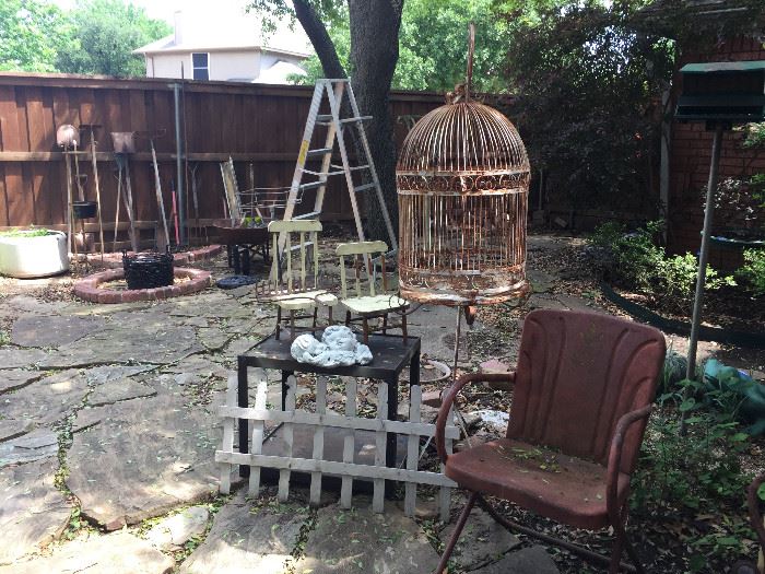 A second bird cage on a stand, metal chair and lots of garden tools