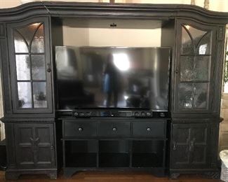 Entertainment Center - $300 This entertainment Center has two 26 inch wide side cabinets with glass doors. Each cabinet has 2 glass shelves and a 3 way light, which is controlled by tapping the hinge on the outside of the door. The 3rd piece is the bridge across the top. When the 3 pieces are attached, the bridge can slide and adjust to fit up to an 80 inch TV. The black console is a separate 60 inch piece. It has 3 drawers and 3 open compartments. Id was not an original piece of the entertainment center, but matches nicely.