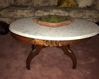 Oval marble top coffee table with carved floral design.
