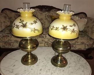 Matching vintage brass lamps with glass shades embellished with metal floral pieces.
