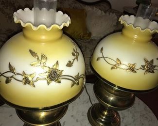 Matching vintage brass lamps with glass shades embellished with metal floral pieces.