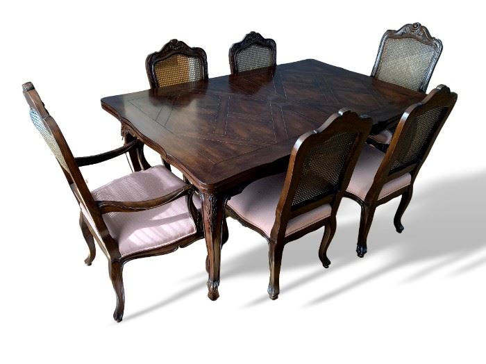 Solid wood dining room table and chairs as shown. Table has slide out leaves on each side.  Shows wear - cane chair backs show damage.  Table measures 67 inches long by 44 inches wide. 