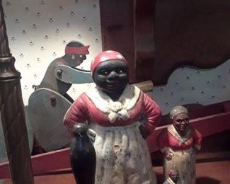 Three cast iron figures and a carved and painted whirl-i-gig in background.