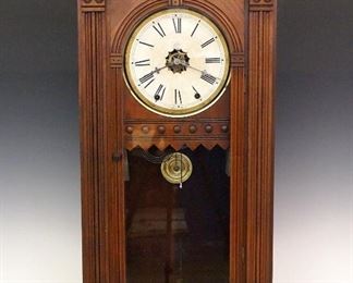 A late 19th century Waterbury "Elberon" Model Shelf Clock.  8-day weight driven time and strike movement with a papered metal dial.  Walnut case with molded crown and base and a single long door with arched top.