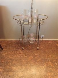 Adorable rolling brass and glass bar cart. Crystal glassware and decanters