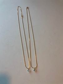 A pair of gold tone necklaces with light blue stone