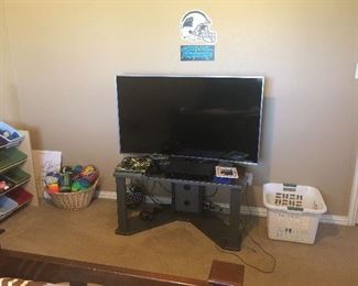 Flatscreen TV on stand, and plastic bin toy cubby storage