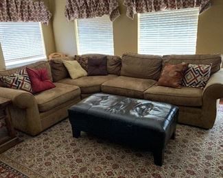 Pottery Barn Upholstered L-shaped sectional sofa, coordinating throw pillows, and large leather tufted ottoman / coffee table