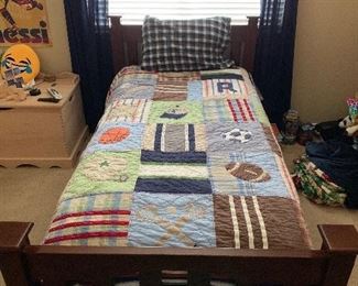 Twin bed with wooden headboard / foot board, and sports related quilted bedding