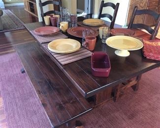 Rustic trestle style farmhouse  dining table with bench seating, and three matching dining chairs