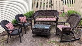  Five piece wicker look patio set  with new cushion set.  Loveseat, two arm chairs, rocking chair, and coffee table with storage.