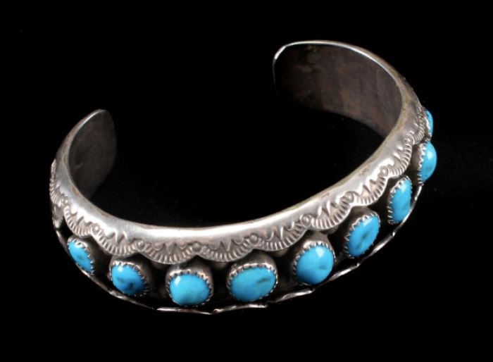Description: Marked on the back: W.M. Sterling. Comprised of 9 turquoise inset stone on a recessed ground and tooled cuff surface. Shipping weight: 2 ounces. Size: Width: 2 3/4 inches.
Dimensions: 9 3/4 inches.