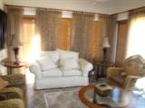 White brocade sofa, wood venetian blinds, lamps, glass and iron table, woven elegant chairs