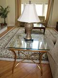 glass and brass table - oriental-style rug - several 'easy chairs'