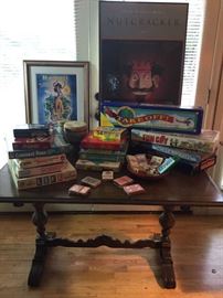 Board games and collectible framed Nutcracker poster, all on a vintage library table 