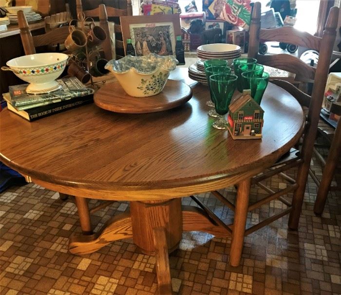 Oak pedestal table with four ladder back chairs, green glassware, enamel strainer, pottery, more!