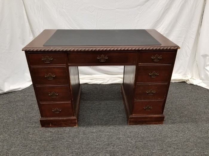 Antique, chocolate colored, wood executive desk. Writing pad included. Approximate dimensions are 44" W X 23" D X 29" H. Please bring proper help and/or equipment for removal.