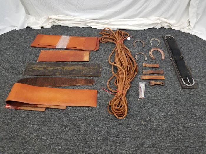 Multiple pieces of assorted hide leathers, approx 50 ft. of full hide thick "rope", horse saddle strap, and horseshoes. Please see pictures for complete lot details.
