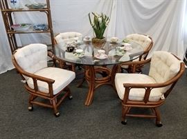 Vintage, 1970's rattan dining room/patio table set from Palm Springs. Thick, glass top table with 4 swivel chairs on rollers with nice, thick, newly upholstered cushions. Would make a great gazebo, pool house, or patio set. Approximate dimensions of table are 48" Diameter by 28.5" height. Heavy duty .5" thick detachable glass tabletop. Qty (4) swivel chairs on wheels. Each chair measures approximately 23" W X 23" D X 17" seat height. X 32" back height. This lot is for the table and chairs only. See matching rattan items in lots 16 and 110. Table decorations NOT included. Please bring help for removal, as the glass top is quite heavy
