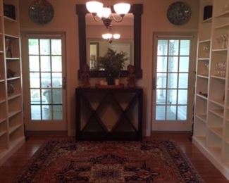 Dining room rug, wine cabinet and large metal mirror. Turkish platters seen on right and left of mirror.