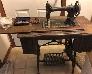 White sewing machine. Foot operated. Cabinet in good condition.