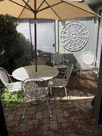 VINTAGE WROUGHT IRON PATIO SET WITH 6 ARM CHAIRS, ROUND TABLE, & UMBRELLA WITH STAND. WHITE WROUGHT IRON WALL SCULPTURE INCLUDED WITH SET.