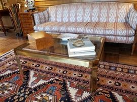 Brass and glass rectangle coffee table and a carved wood frame sofa