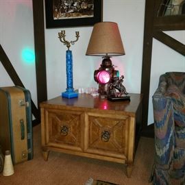 Retro end table with Italian porcelain candlestick and soldier am radio as well as vintage luggage