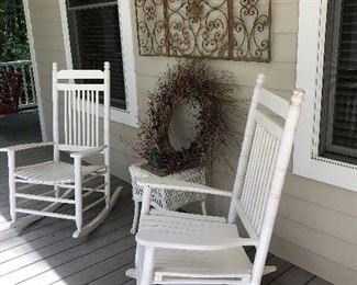 Have a seat on the front porch in these white rockers, also wicker table and metal wall art