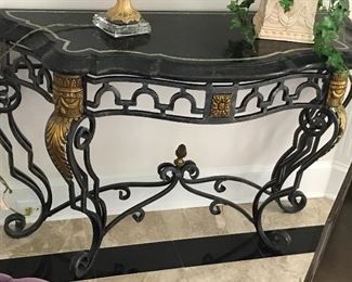 Maitland-Smith Console Table
Approx. Dimensions:  49" x 18½" x 32¾"
Black marble mosaic top with shaped edge, light marble edge banding, set on a curvilinear metal base with steel finish, bright gilt ornaments at the sides and on the pine cone finial below. 